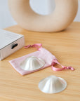 Foto van zilveren tepelhoedjes voor kloven tijdens de borstvoedingsperiode met dustbag en doosje erbij