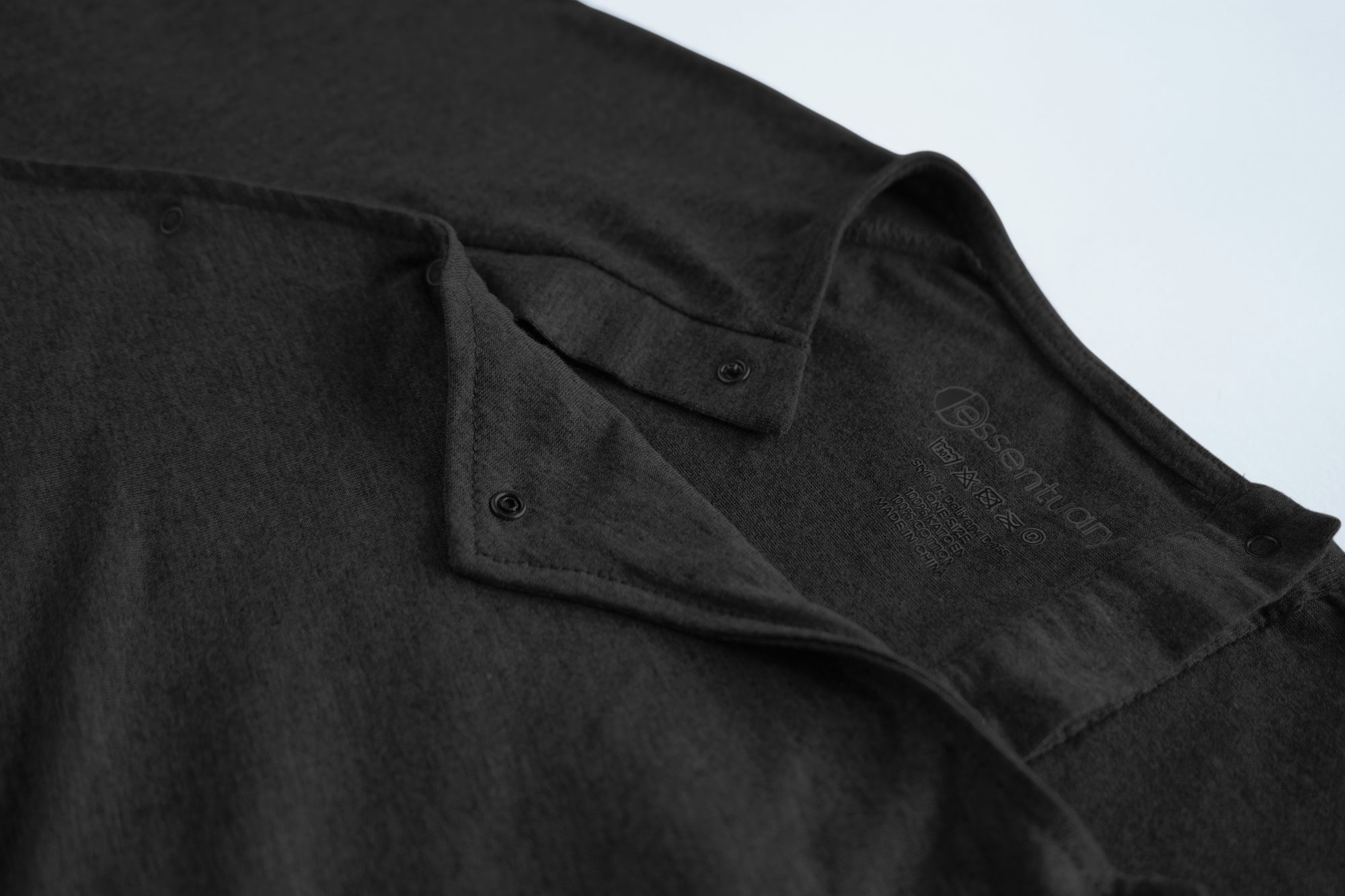 Close-up van de drukknopen en het Essentuary merk in de nek van de zwarte bevallingsjurk en voedingsjurk