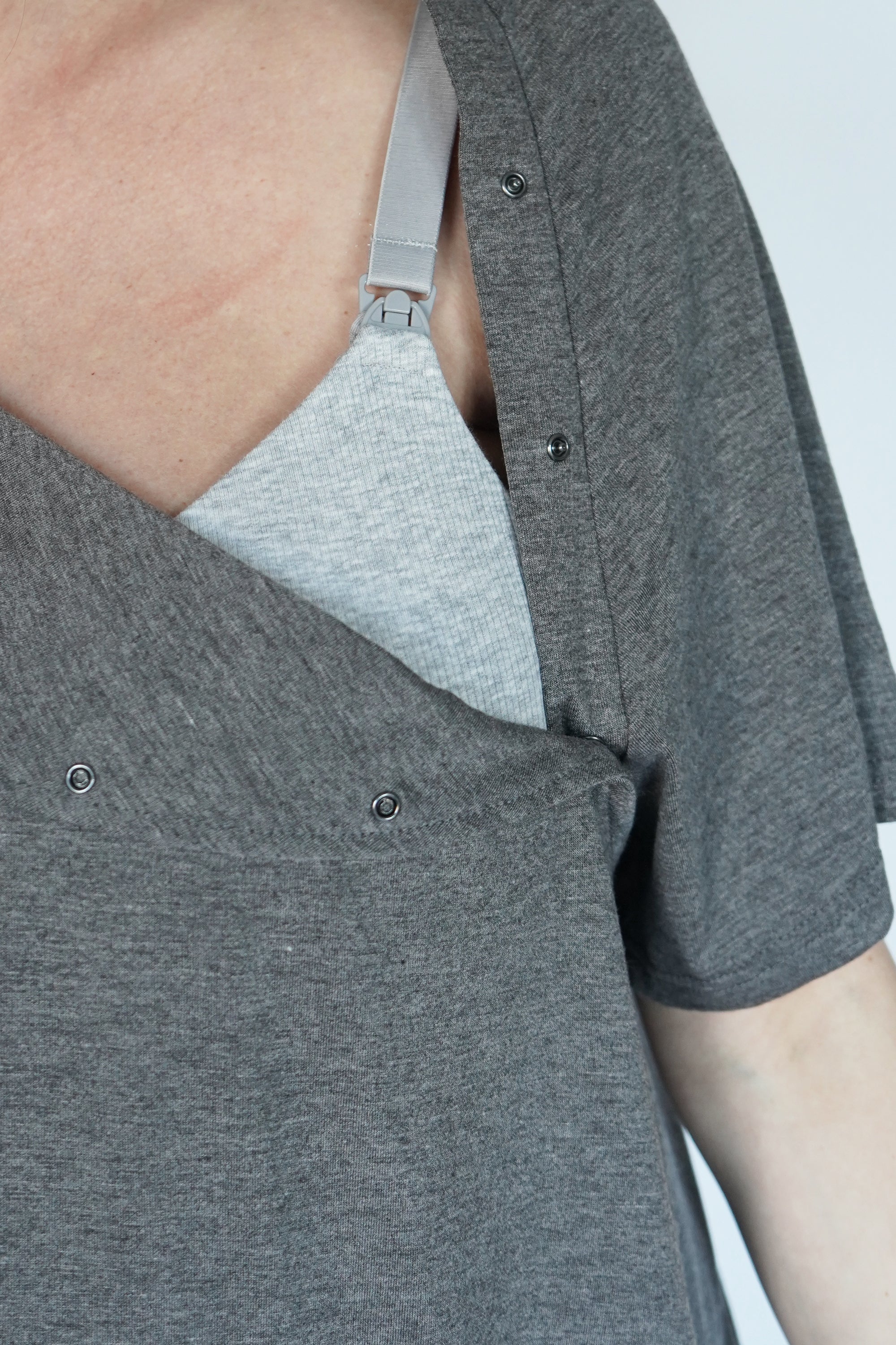 Close-up van de drukknopen op de schouder van de grijze bevallingsjurk en voedingsjurk, voor gemakkelijke toegang tijdens borstvoeding.