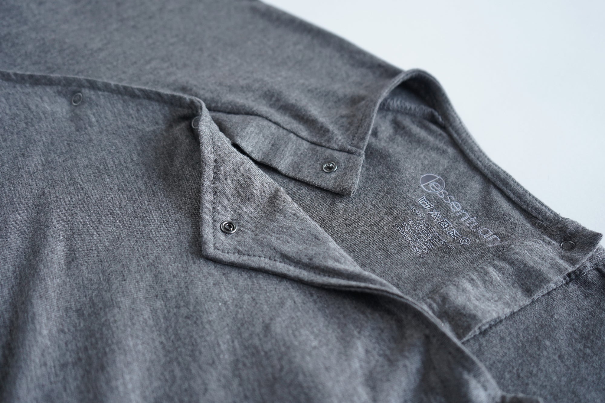 Close-up van de drukknopen en het Essentuary merk in de nek van de grijze bevallingsjurk en voedingsjurk