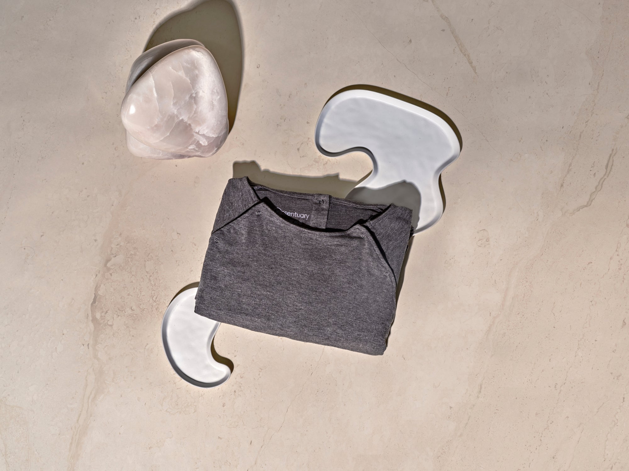 Grijze bevallingsjurk opgevouwen, toont compacte formaat en label-vrij ontwerp om irritatie te voorkomen.