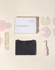 Overzicht van Essentuary postpartum essentials in de Ode to Motherhood Box, met de bostkompressen, kraamverband, Peri Bottle en de bevallingsjurk