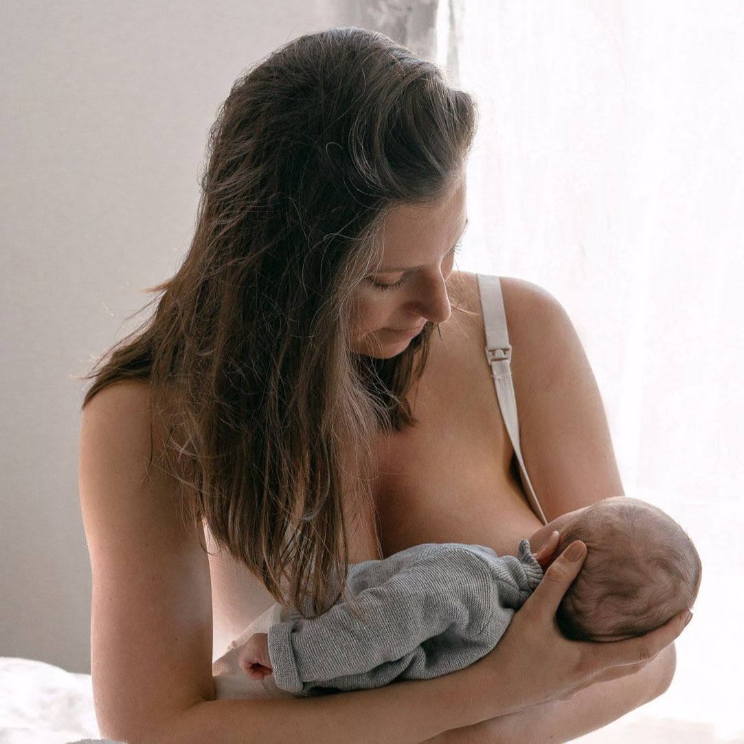 Kraamvrouw met jonge baby geeft borstvoeding op een kraambed