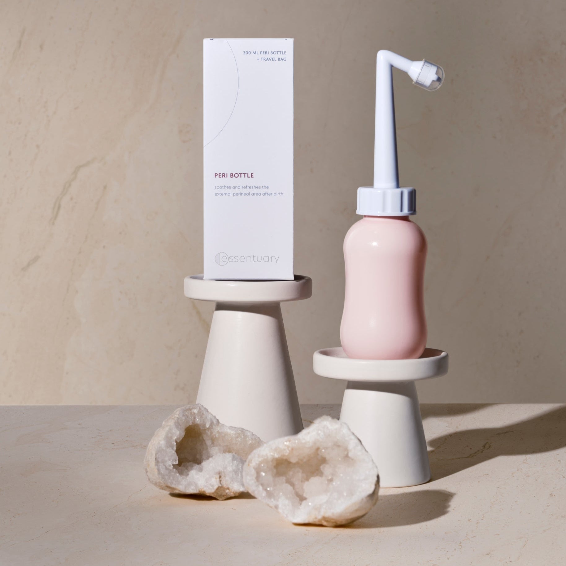 Essentuary Peri Bottle naast verpakking, in een mooi sfeerbeeld dat het merk vertegenwoordigt
