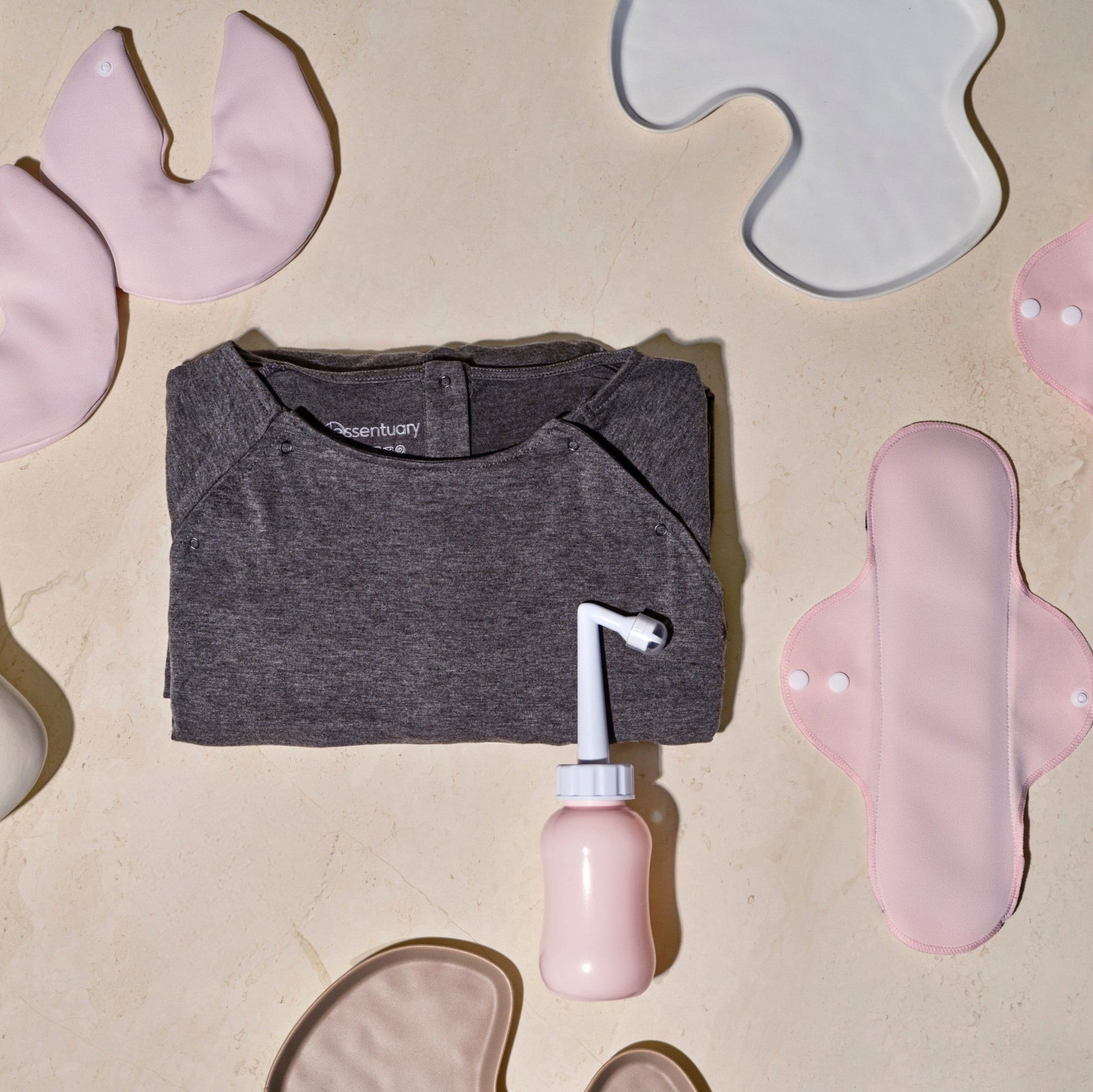 Overzicht van Essentuary postpartum essentials voor in elk vluchtkoffer, met de Peri Bottle, de bostkompressen, het kraamverband en de bevallingsjurk