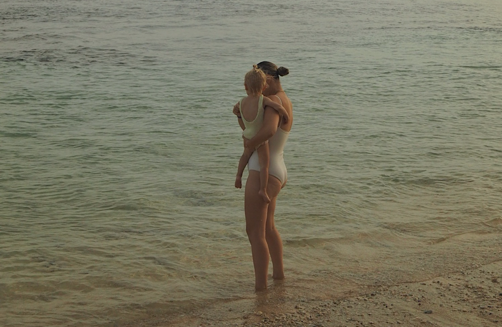 Jonge postpartum moeder met baby in de zee