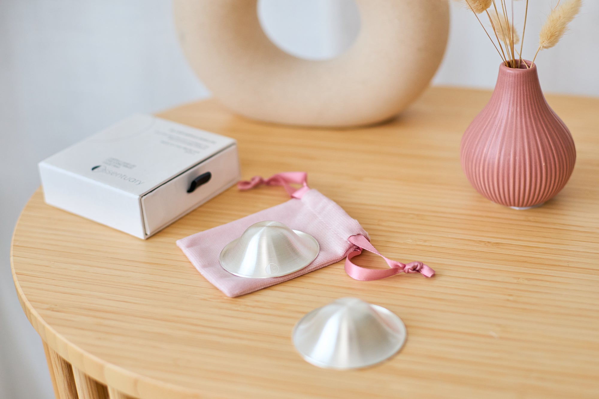 Foto van zilveren tepelhoedjes voor kloven tijdens de borstvoedingsperiode met dustbag en doosje erbij