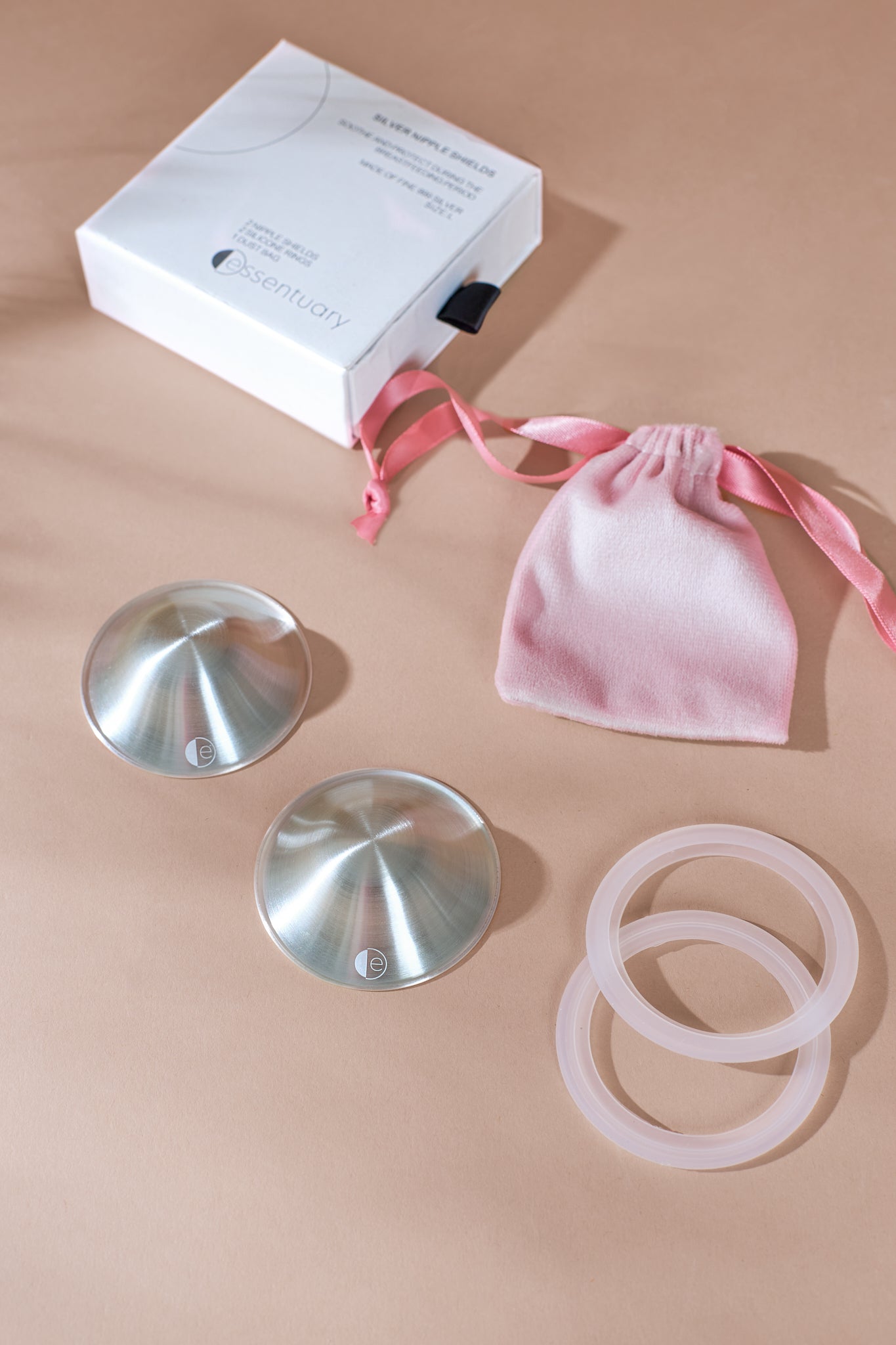 Foto van zilveren tepelhoedjes met dustbag, siliconen ringen en doosje voor kloven tijdens de borstvoedingsperiode