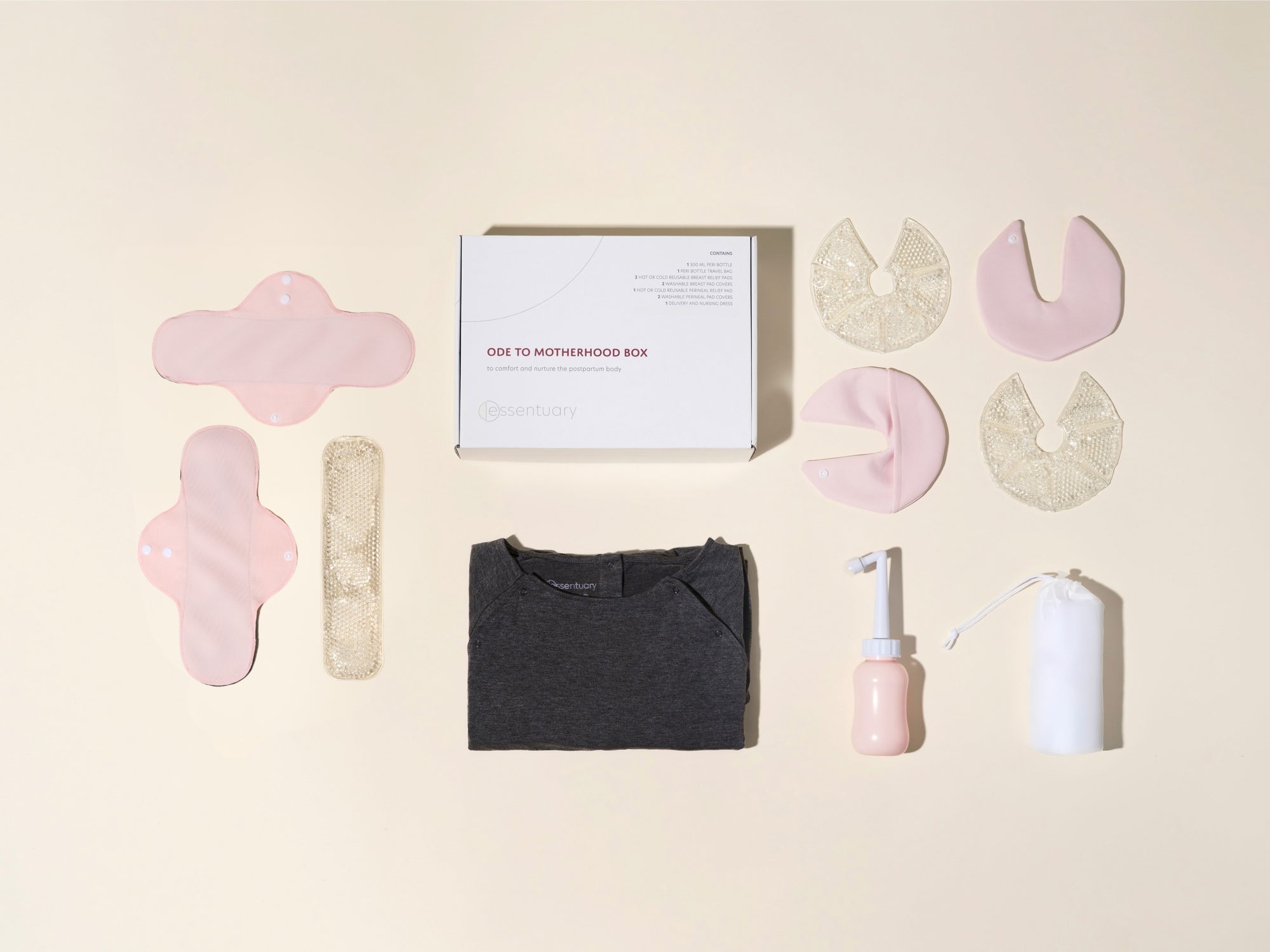 Overzicht van Essentuary postpartum essentials in de Ode to Motherhood Box, met de grijze bevallingsjurk, bostkompressen, kraamverband en de Peri Bottle