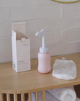 Video van een peri bottle op de wastafel met doos voor zachte reiniging van het perineum na de bevalling, met ergonomisch ontwerp en gebogen sproeituit.