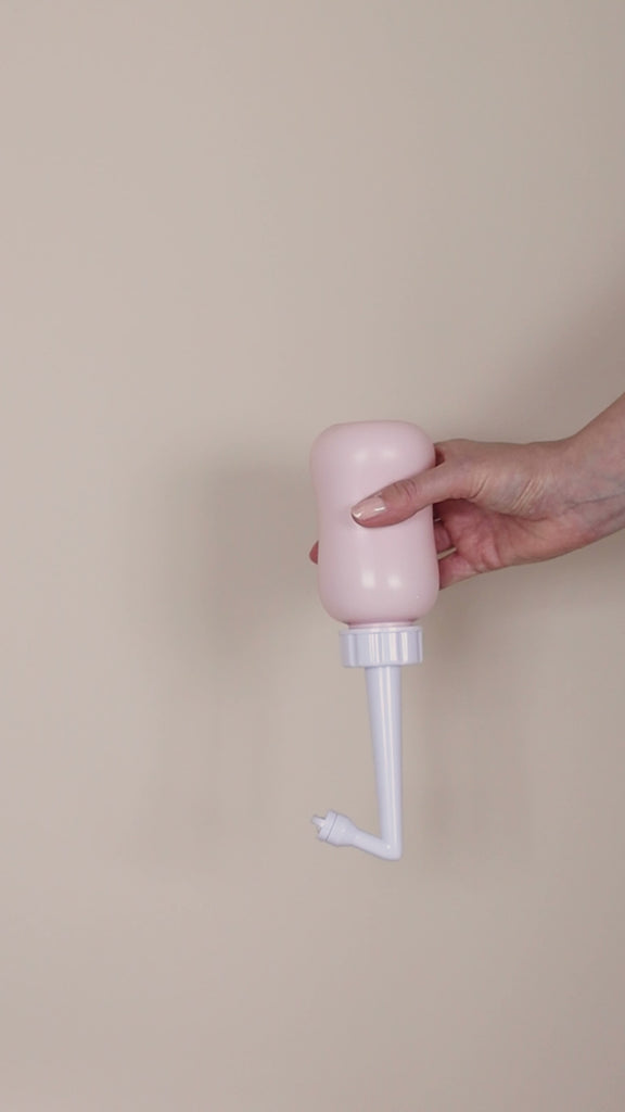 Video van een peri bottle op zijn kop voor zachte reiniging van het perineum na de bevalling, met ergonomisch ontwerp en gebogen sproeituit.